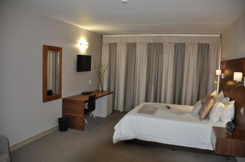 a hotel room with a large bed and a desk at Merchant Business Class Hotel in Henley on Klip