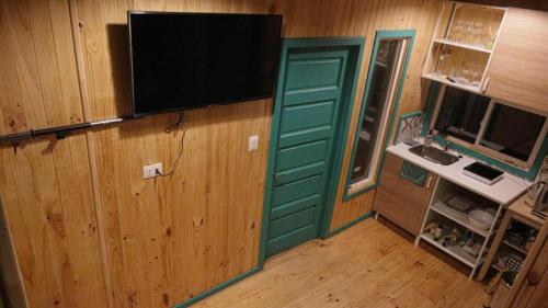 a room with a green door and a television on a wall at Tiny Fuy in Puerto Fuy