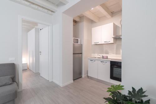 eine Küche mit weißen Schränken und einem Sofa in einem Zimmer in der Unterkunft Palazzetto Vittoria - F&L Apartment in Brescia