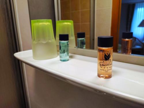 a bathroom counter with bottles of soap and a mirror at Pension Forelle in Forbach
