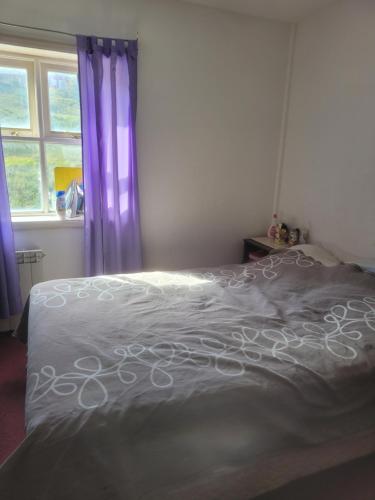 1 dormitorio con cama blanca y cortinas moradas en Habitacion privada en casa en Ushuaia