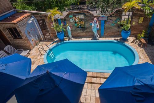 Eine Frau steht neben einem Pool mit Sonnenschirmen in der Unterkunft Pousada Ecos do Mar in Praia do Frances