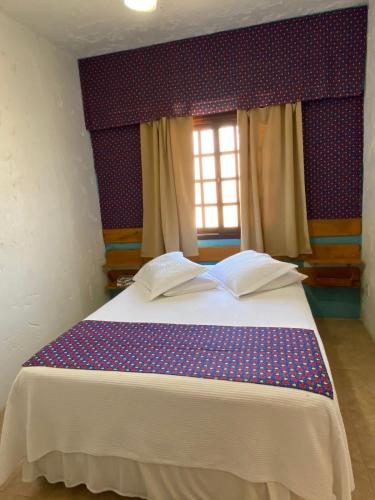 a bedroom with a bed with two books on it at POUSADA MORADAS DO JAU in Hermenegildo