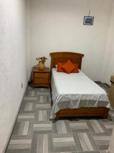 ケレタロにあるHabitación privada peñaのベッドルーム1室(オレンジ色の枕が付いたベッド1台付)