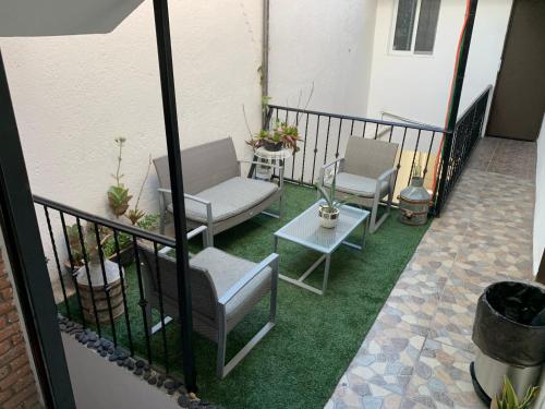 uma varanda com 2 cadeiras e uma mesa sobre relva em Habitación privada peña em Querétaro