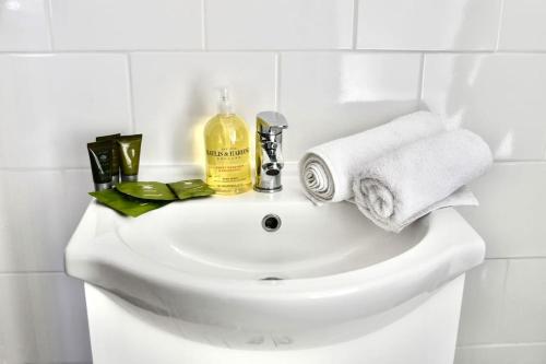 biała umywalka z ręcznikami i butelka mydła w obiekcie The Copperfield Apartment - Broadstairs Central - By Goldex Coastal Breaks w mieście Kent