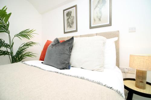 a bedroom with a bed with pillows and a plant at Long stay offer - Stylish 1 bed flat with parking in Bristol