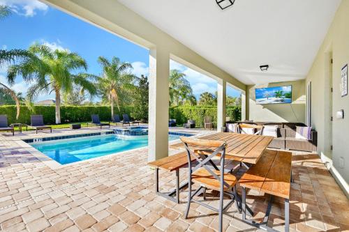 un patio con mesa de madera y sillas junto a una piscina en Marvelous Home Near Disney With Private Pool And Waterpark & Resort Access At Encore Resorts Reunion - 250Cl, en Kissimmee