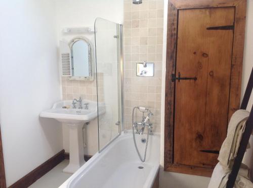 een badkamer met een bad, een wastafel en een douche bij The Long Barn in Skibbereen
