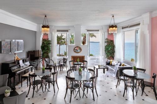 un restaurant avec des tables et des chaises et l'océan dans l'établissement Aneroussa Beach Hotel, à Batsi