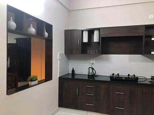 a kitchen with brown cabinets and black counter tops at Urbane Cove in Trivandrum
