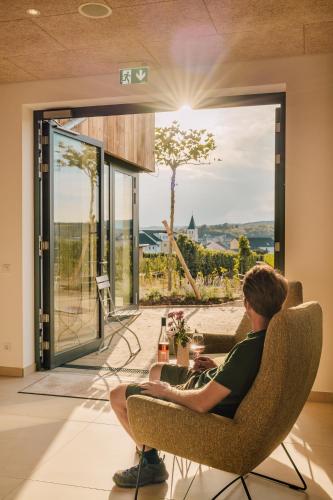 a man sitting in a chair in front of a window at Zeit bei Sauerweins in Palzem