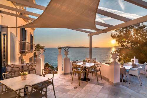 a patio with tables and chairs and a view of the ocean at Aneroussa Beach Hotel in Batsi