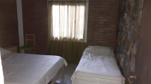 1 dormitorio con 2 camas y ventana en Cabaña pared de piedra en Carpintería