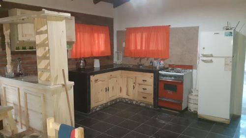 cocina con armarios de madera y nevera blanca en Cabaña pared de piedra en Carpintería