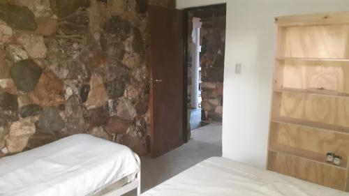 1 dormitorio con pared de piedra y 2 camas en Cabaña pared de piedra en Carpintería