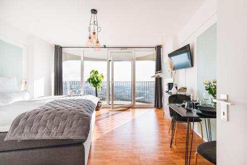a bedroom with a large bed and a desk with a monitor at GREAT CITY VIEW I 26 FLOOR I NETFLIX and BOXSPRINGBED in Augsburg