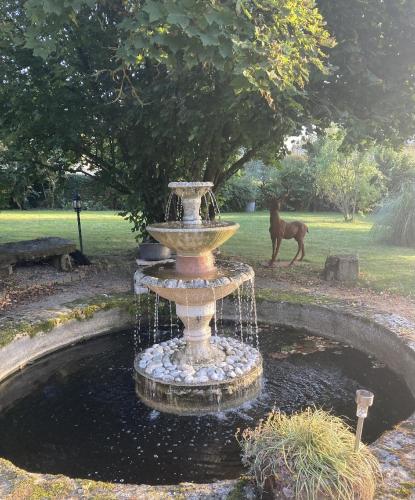 a fountain in a yard with a horse in the background at Le Clos d'Albray - Chambres d'hôtes et gite in Comps-la-Grand-Ville