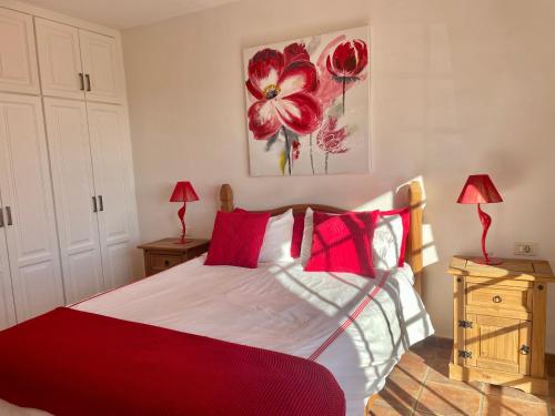 Villa Consuelo - Quiet Location Close to Resorts في Buzanada: غرفة نوم بسرير احمر وبيض ومخدات حمراء