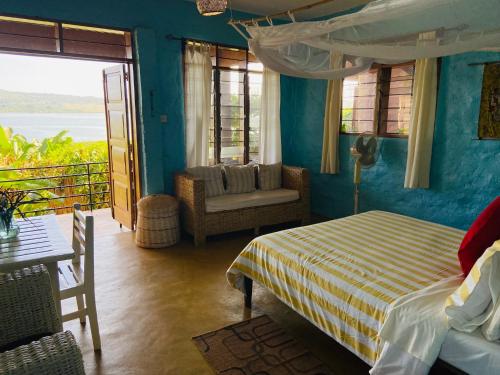 Home On The Nile water front Cottage في جينجا: غرفة نوم بسرير وطاولة وكرسي