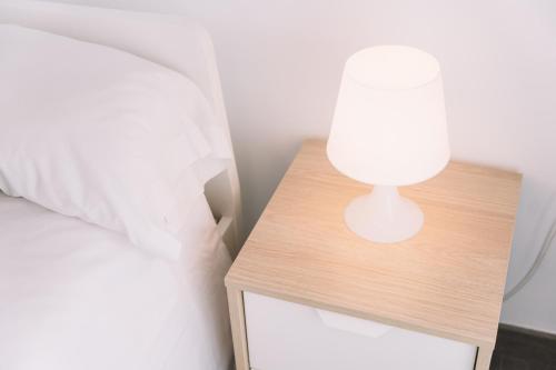 a white lamp on a nightstand next to a bed at Home Málaga in Málaga