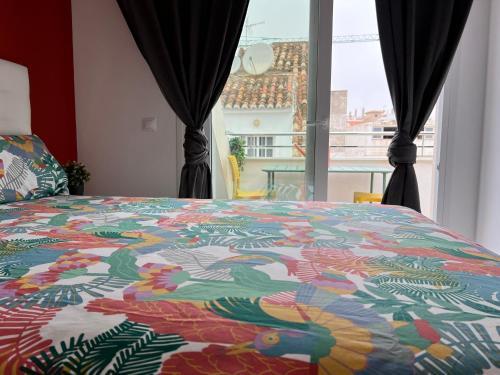 a bed with a colorful comforter in front of a window at Bnbook Medea Apartments 2 in Fuengirola