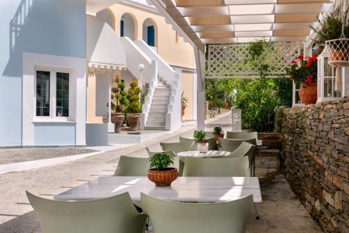 a restaurant with white tables and white chairs at Aneroussa Beach Hotel in Batsi