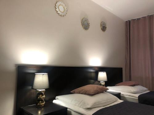 a bedroom with two beds and two lamps on the wall at Sosnowe Zacisze in Białystok