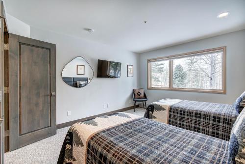1 Schlafzimmer mit 2 Betten, einem Spiegel und einem Fenster in der Unterkunft Three-Bedroom Townhouse in Beaver Creek
