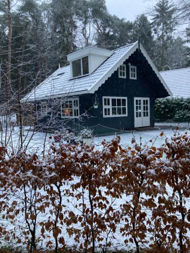 een zwart huis met een met sneeuw bedekt dak bij Het Veenhuisje in Norg