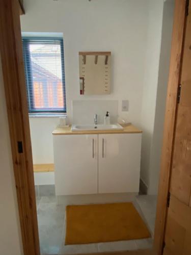 a white bathroom with a sink and a window at Wood Farm Barn in Laxfield