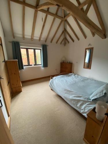 a bedroom with a blue bed and a window at Wood Farm Barn in Laxfield