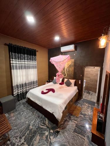 a bedroom with a bed with a pink umbrella on it at Ceylon Resort in Wilpattu