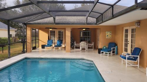a patio with a swimming pool with chairs and an open roof at Family Vacation Home With Pool and Spa Near Disney and Universal in Orlando