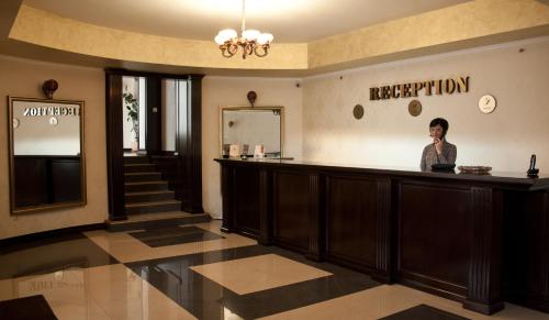 a woman standing at a bar in a lobby at Hotel Majestic in Iaşi
