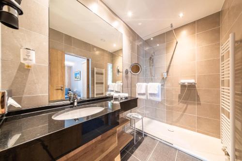 La salle de bains est pourvue d'un lavabo et d'un miroir. dans l'établissement Koener Hotel & Spa, à Clervaux