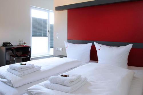 a bedroom with two white beds with towels on them at Hotel VielHarmonie in Jena