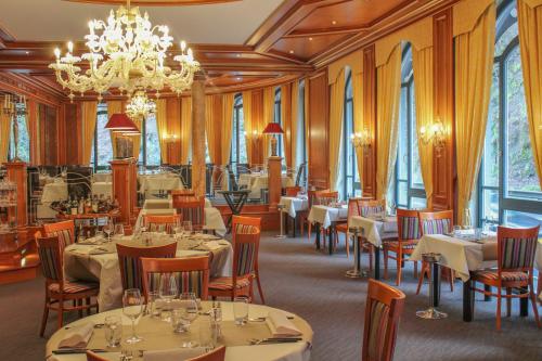 un restaurante con mesas y sillas y una lámpara de araña en Koener Hotel & Spa en Clervaux