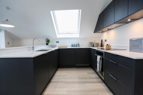 a kitchen with black cabinets and a window at Ocean View - Bracklesham Bay in Chichester