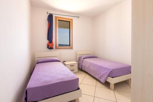 2 Betten in einem Zimmer mit violetter Bettwäsche und einem Fenster in der Unterkunft Appartamenti Marinelli - Santa Maria di Leuca in Santa Maria di Leuca