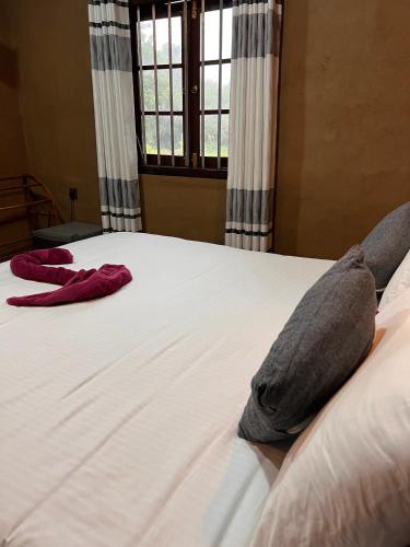 a bed with two pillows on it with a window at Ceylon Resort in Wilpattu