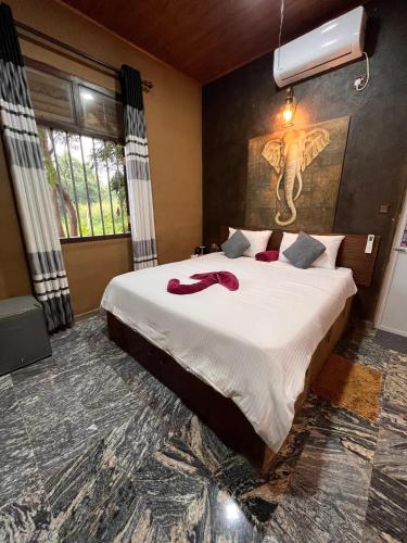 a bedroom with a large white bed with a painting on the wall at Ceylon Resort in Wilpattu