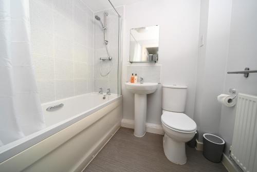 La salle de bains blanche est pourvue de toilettes et d'un lavabo. dans l'établissement Ideal Coach House, à Swindon