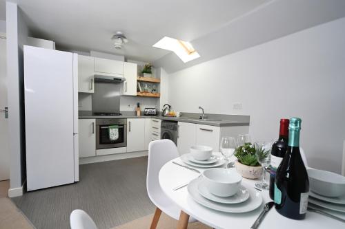 a white kitchen with a white table and white chairs at Ideal Coach House in Swindon