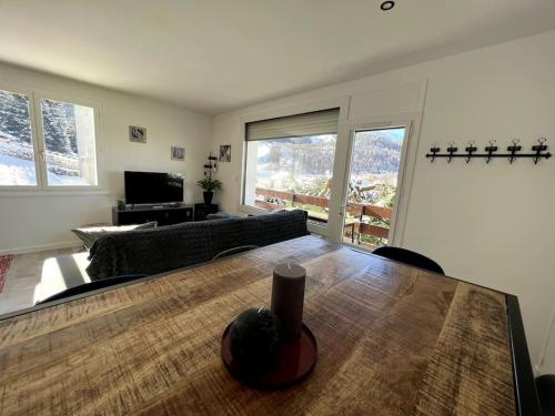 uma sala de estar com uma mesa e um sofá em Appartement cocooning 2 chambres em Gourette