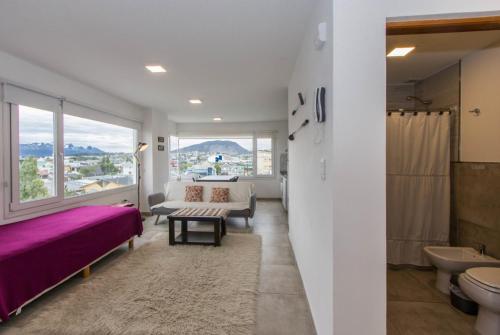 1 dormitorio con cama morada y ventana grande en Walanika Apartamentos en Ushuaia