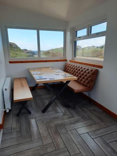 a room with a table and a bench and two windows at NC500 - Modern croft house at Handa HI-00734-F in Scourie