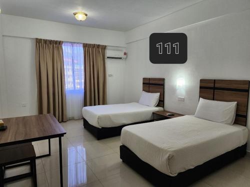Habitación de hotel con 2 camas y escritorio en Hotel Meligai Kapit, en Kapit