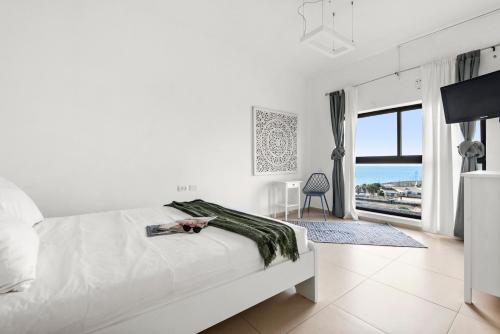 a white bedroom with a bed and a view of the ocean at GLORIOUS renovated apartment on top of the beach in Tel Aviv