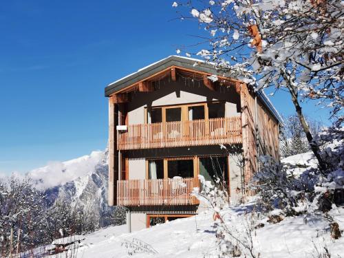 um chalé de madeira com uma varanda na neve em Chalet le 1000 Thabor em Valmeinier